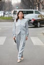 Woman with cold gray jacket and trousers with square pattern and golden necklace and earrings