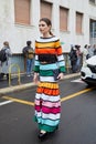 MILAN, ITALY - FEBRUARY 26, 2023: Woman with colorful striped dress in yellow, orange, turquoise, green and black Cambiaghi bag