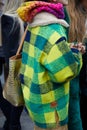 MILAN, ITALY - FEBRUARY 22, 2023: Woman with green and yellow checkered jacket and golden crocodile leather bag before Fendi