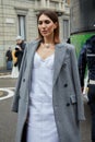 Woman with grey coat and white dress before Philosophy by Lorenzo Serafini fashion show, Milan