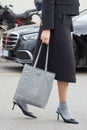 MILAN, ITALY - FEBRUARY 23, 2023: Woman grey leather Prada bag and black high heel shoes before Prada fashion show, Milan Fashion