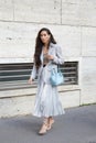 MILAN, ITALY - FEBRUARY 25, 2023: Woman with light blue bag, silver pleated skirt and grey jacket before Missoni fashion show,