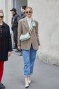 MILAN, ITALY - FEBRUARY 23, 2023: Woman with light green leather Prada bag before Prada fashion show, Milan Fashion Week street