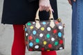 MILAN, ITALY - FEBRUARY 23, 2023: Woman with Louis Vuitton bag with colorful polka dots before Prada fashion show, Milan Fashion