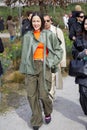 MILAN, ITALY - FEBRUARY 25, 2023: Woman with orange shirt and green leather jacket before Ferragamo fashion show, Milan Fashion