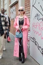 MILAN, ITALY - FEBRUARY 22, 2023: Woman pink raincoat, headscarf and transparent dress before Fendi fashion show, Milan Fashion