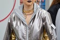 MILAN, ITALY - FEBRUARY 22, 2023: Woman with silver jacket and golden and silver snake necklace before Fendi fashion show, Milan