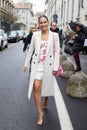 MILAN, ITALY - FEBRUARY 26, 2023: Woman with white coat and dress with floral decoration before Luisa Spagnoli fashion show, Milan