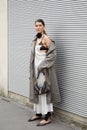 MILAN, ITALY - FEBRUARY 23, 2023: Woman with white dress and grey trench coat before Prada fashion show, Milan Fashion Week street