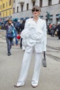 Woman with white jacket and trousers with big flower before Dolce and Gabbana fashion show,