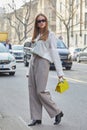 Woman with white shirt, grey trousers and yellow bag before Fendi fashion show, Milan Fashion