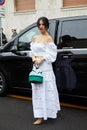 MILAN, ITALY - FEBRUARY 26, 2023: Woman with white top, skirt and striped bag before Luisa Spagnoli fashion show, Milan Fashion