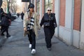 Man with beige coat and woman with black Chanel bag walking before Fendi fashion show, Milan