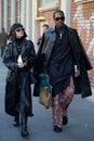Woman with black leather trench coat and man with black, long shirt before Fendi fashion show,