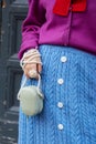 Woman with blue wool skirt, purple sweater and bag with pearls strap before Reshake fashion show