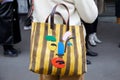Woman with brown and yellow striped bag and abstract face before Marco de Vincenzo fashion show