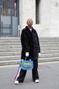 Woman with dark fur coat and colorful leather bag before Frankie Morello fashion show, Milan