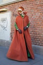 Woman with green velvet shirt and trousers and orange cloak before Fendi fashion show, Milan