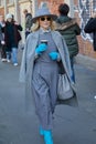 Woman with grey dress and hat and turquoise gloves before Fendi fashion show, Milan Fashion Week