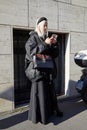 Woman with large, black bomber jacket and Gucci bag looking at smartphone before Etro fashion