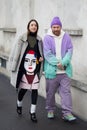 Woman and man with gray fur and purple and turquoise soft gradient sweater before Prada fashion