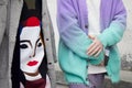 Woman and man with gray fur and purple and turquoise soft gradient sweater before Prada fashion