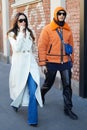 Woman with white coat and man orange coat and hoodie before Fendi fashion show, Milan Fashion