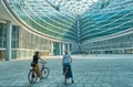 Milan ITALY - July 2019 two woman exploring the city by bicycle Abstract structures of a Modern building glass