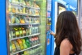 MILAN, ITALY - JULY 19, 2017: Unidentified young student or female tourist choosing a snack or drink at vending machine at night i