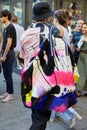 Man with bag in pink, black and blue colors and shirt with crane birds design before Palm Angels