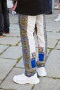 Man with white sneakers and trousers with intricate decoration before Les Hommes fashion show, Milan