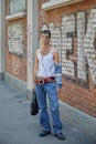 Man with white tank top with safety pins and blue denim trousers before Fendi fashion show, Milan