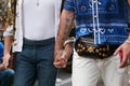 Men hand in hand with Versace shirt walking before Versace fashion show, Milan Fashion Week street