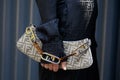 Woman with brown logo pattern Fendi bag and black shirt before Fendi fashion show, Milan