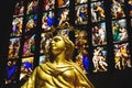 Golden statue of holy woman with colourful window art in background in the Cathedral of Milan, Italy