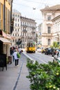 Milan. Old Yellow MIlan Tram. Street Panorama with Pedestrians and Cars on a Sunny Day