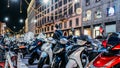 Rows of parked motor scooters in Milan at night. Vespas are an iconic Italian type of transport common in Italy