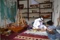 Artisan from Qatar in traditional clothes creating handmade wooden model of ships