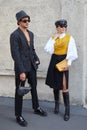 Man with black leather Dior bag and woman with yellow Prada bag before Prada fashion show,