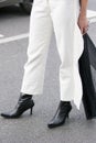 Model wearing a pair of white trousers and a pair of black leather boots