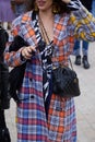 Woman with black leather Chanel bag and checkered colorful coat before Gucci fashion show,