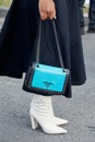 Woman with blue leather Prada bag with studs and white boots before Prada fashion show, Milan