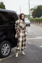 Woman with checkered overalls and jacket in beige and brown colors before Gucci fashion show,