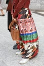 Woman with colorful silk skirt and brown leather bag before Sportmax fashion show, Milan