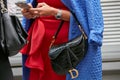 Woman with Dior black crocodile bag and Rolex Submariner watch with gems looking at smartphone