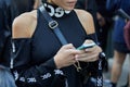 Woman with Disgiusto black street wear shirt looking at smartphone before Bottega Veneta