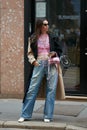 Woman with faded blue denim trousers and pink metallic Balenciaga leather bag before Calcaterra