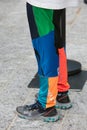 Woman with gray Nike sneakers and trousers in blue, orange, green and black colors before