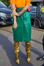 Woman with green reptile leather bag, golden boots and orange shirt before Tods fashion show,