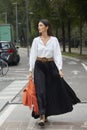 Woman long, pleated skirt and orange bag with fringes before Sportmax fashion show, Milan